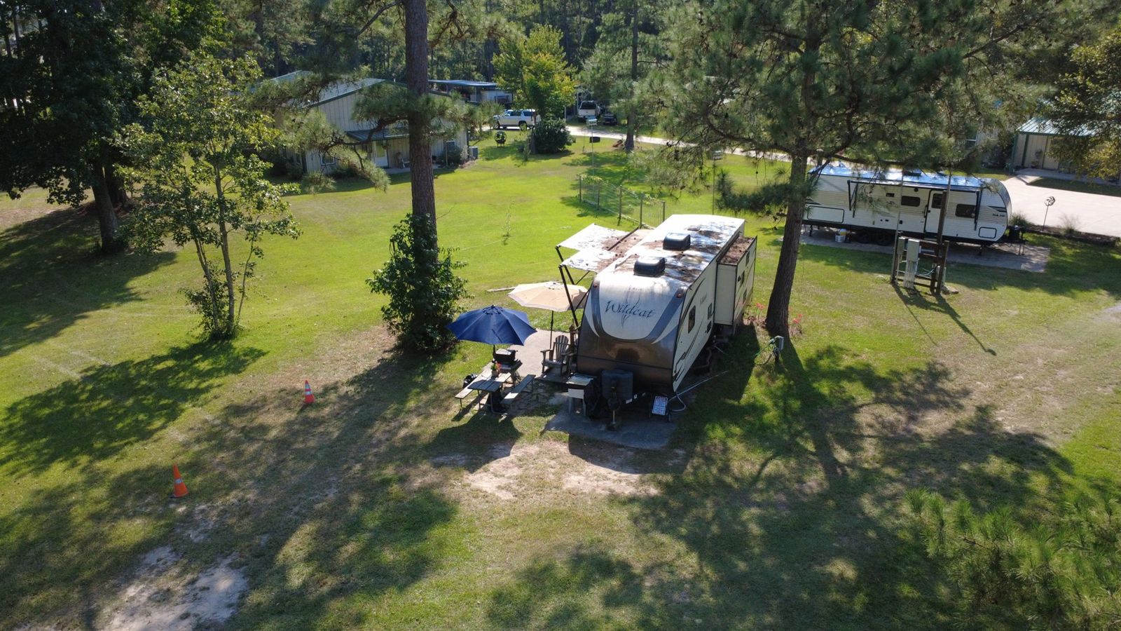 Shaded full-hookup RV site under pine and oak trees at Red Cloud RV Park