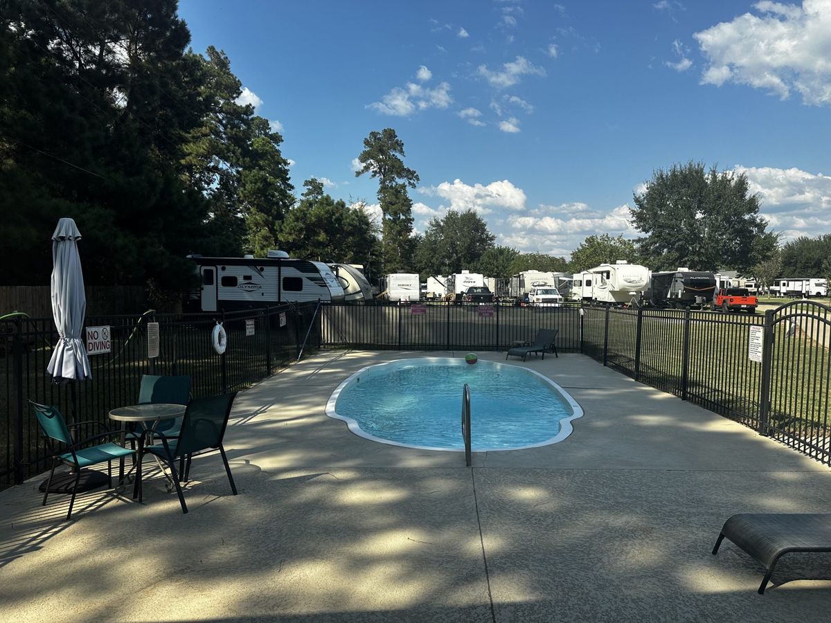 Fenced swimming pool at Red Cloud RV Park in Silsbee TX with lounge chairs